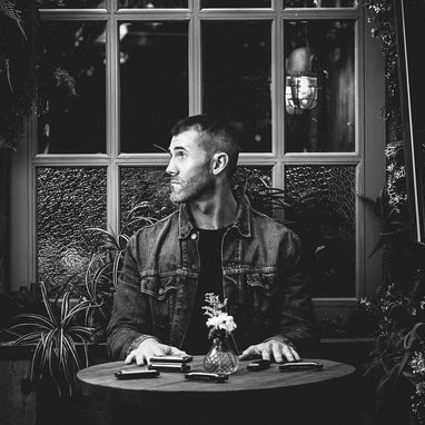 Dan Murphy portait, black and white photograph in profile, with a selection of harmonicas displayed in the table in front of him in different keys