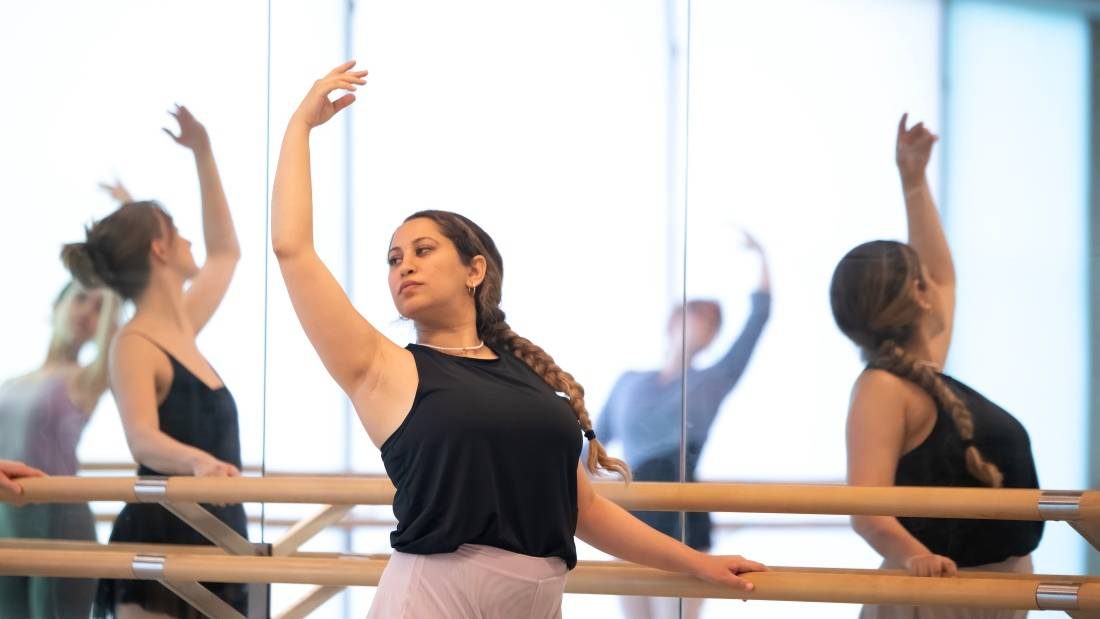 ballet dancers with arms raised at the bar during ballet introduction classes