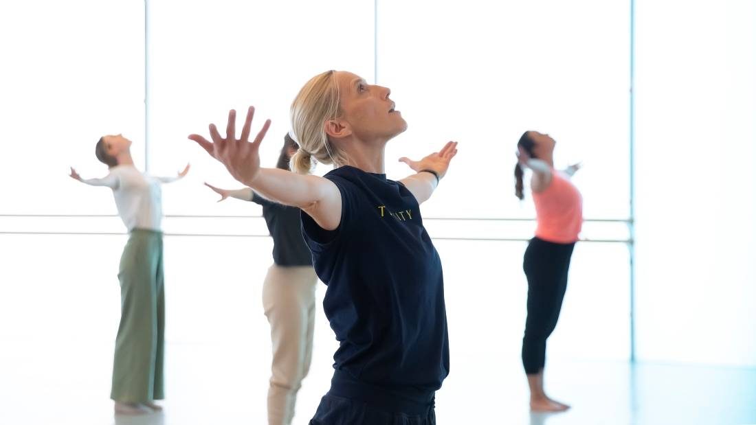 Contemporary Level 2 Saturday Dance class at Trinity Laban, dancers arms stretched out wide, fingers stretched, faces up to the high studio ceiling