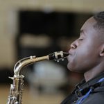 Young man playing the saxophone, in profile with eyes closed in concentration