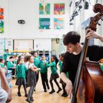 A group of school children listen to jazz music played by Trinity Laban undergraduate students.
